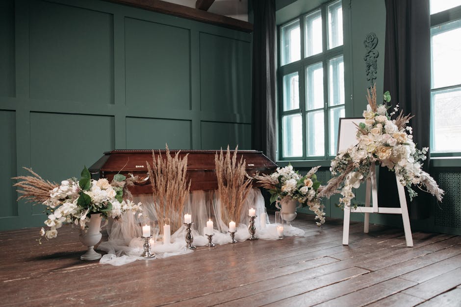 A floral arrangement featuring predominantly white flowers, including roses and lilies, arranged in large white vases on either side of a wooden piano. The composition includes soft beige and cream-co
